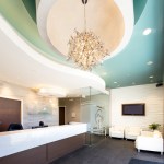 Low-angle view of a bright reception area featuring a large decorative crystal chandelier suspended from a turquoise circular ceiling feature.